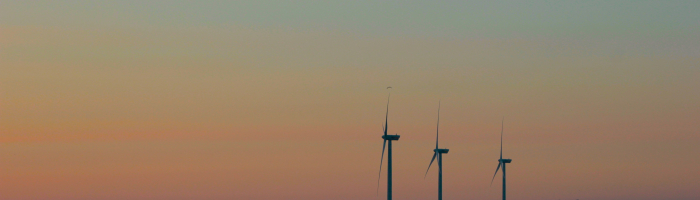 silhouette of three wind turbines at dawn